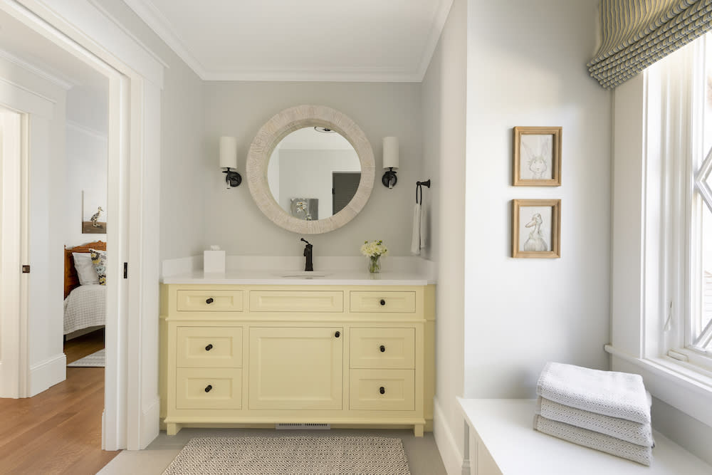Bright and sunny bathroom with oversized yellow vanity and window seat. 