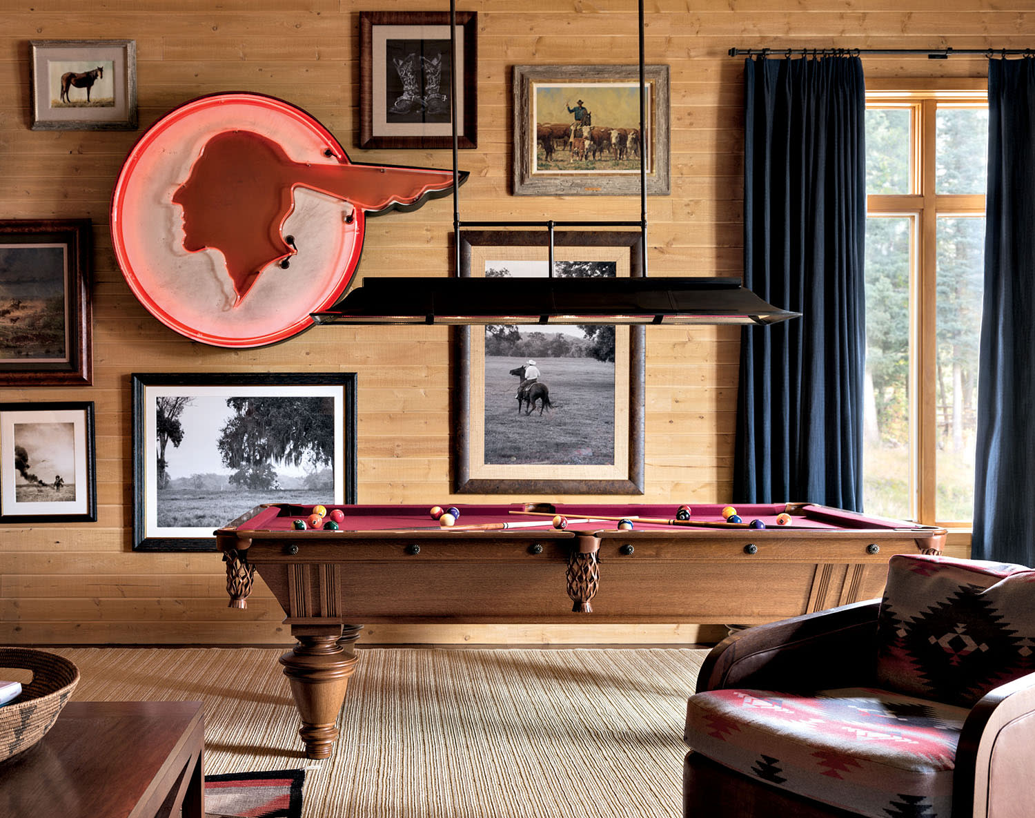 game room with a red billiards table in front of a wall showcasing framed photography and a neon sign
