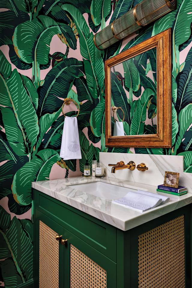 powder room with green banana leaf-print wallpaper, white sink and wood-framed mirror in home by Sara McCann