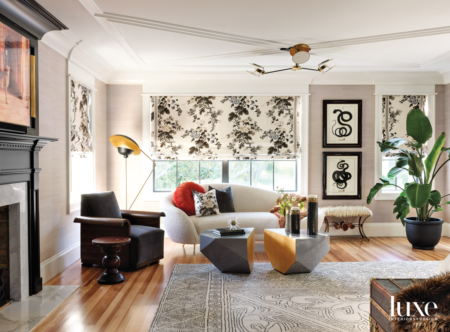 bedroom sitting area with white sofa, dark armchair, patterned draperies and two coffee tables