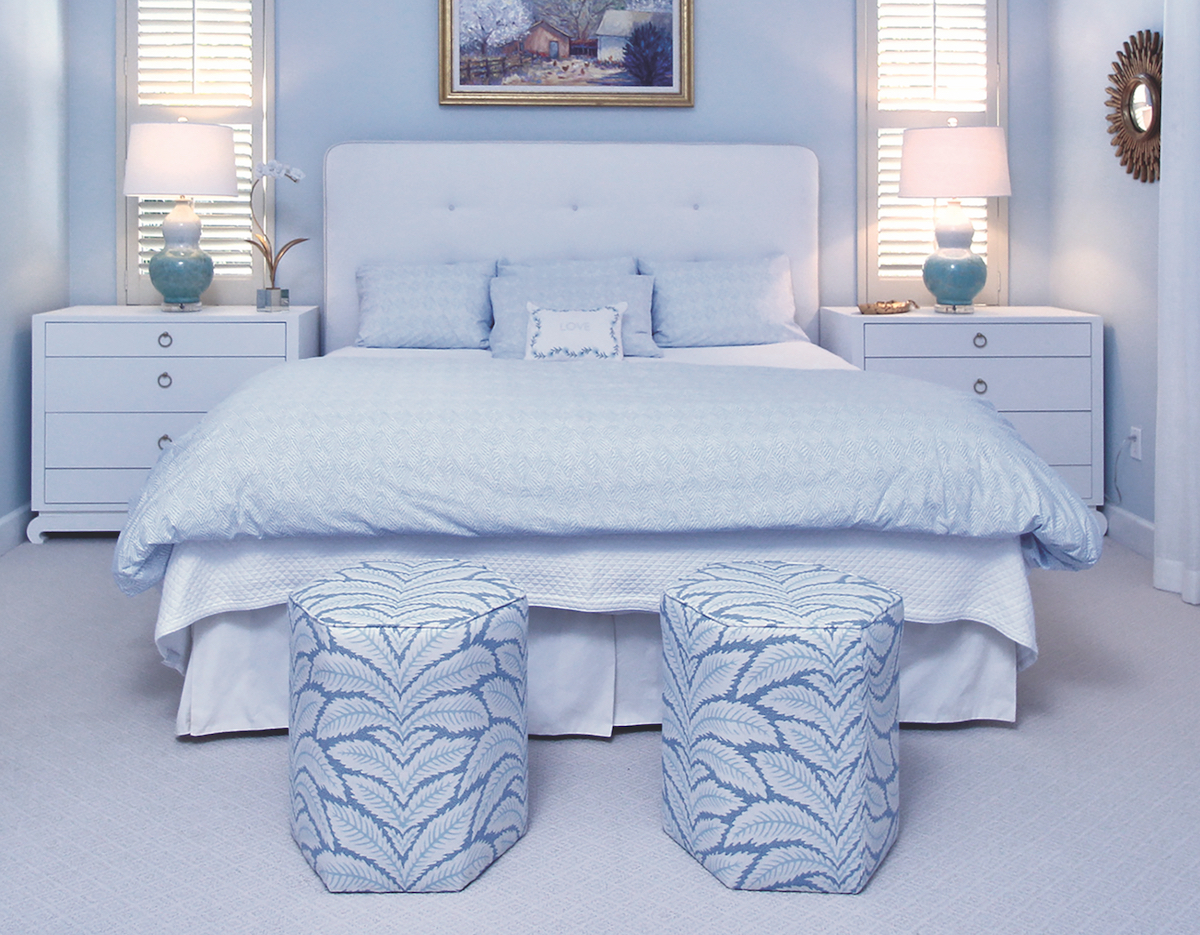 Bedroom, two stools at the foot of the bed, white bedding.