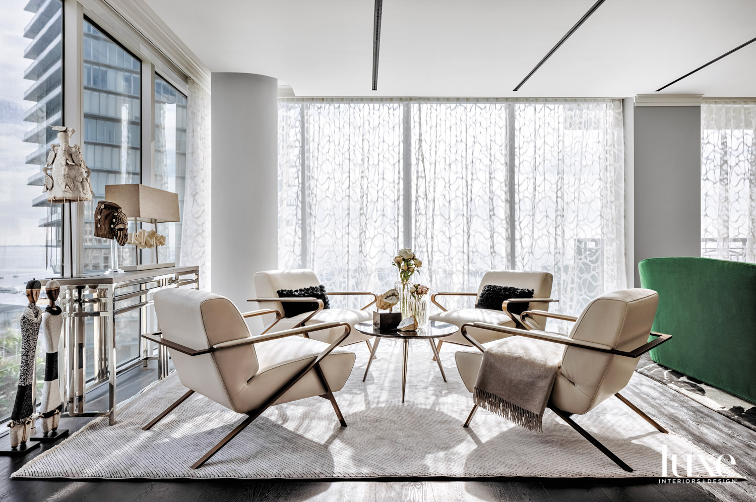 high-rise living area with four armchairs, coffee table and white rug