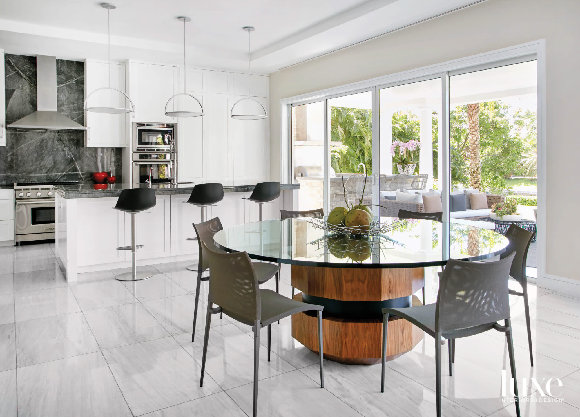 white kitchen with black barstools and breakfast area with round glass table