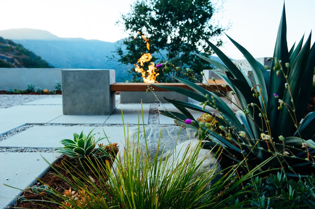 A fire pit nestled in a garden, accompanied by a bench and vibrant plants, ideal for relaxation and gatherings.
