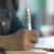 Main tenant un stylo Nash deluxe blanc imprimé d'icônes colorées de réseaux sociaux au-dessus d'un carnet