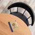 Recycled notebook with tree logo on a wooden table beside a black chair