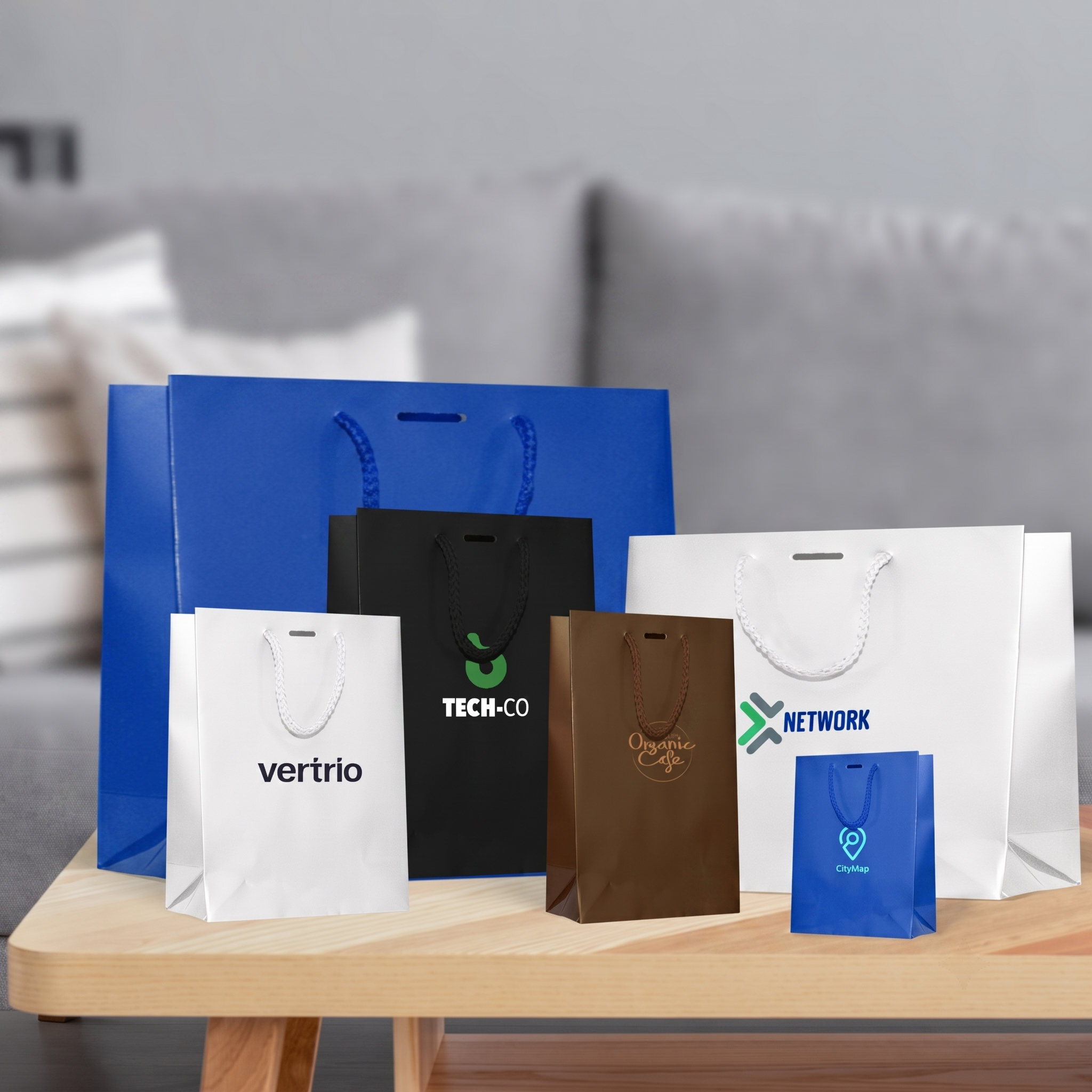 Five luxury paper bags with vertrio, TECH-CO and NETWORK prints in a modern living room scene