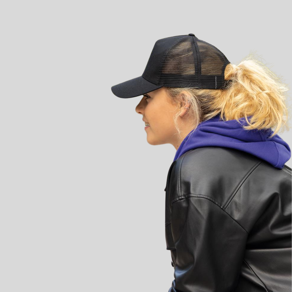 Side view of a woman wearing a black mesh-back trucker cap