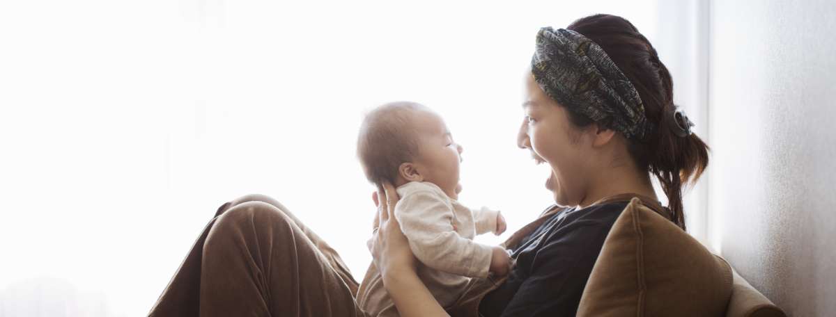 Child care provider holding an infant on the couch.