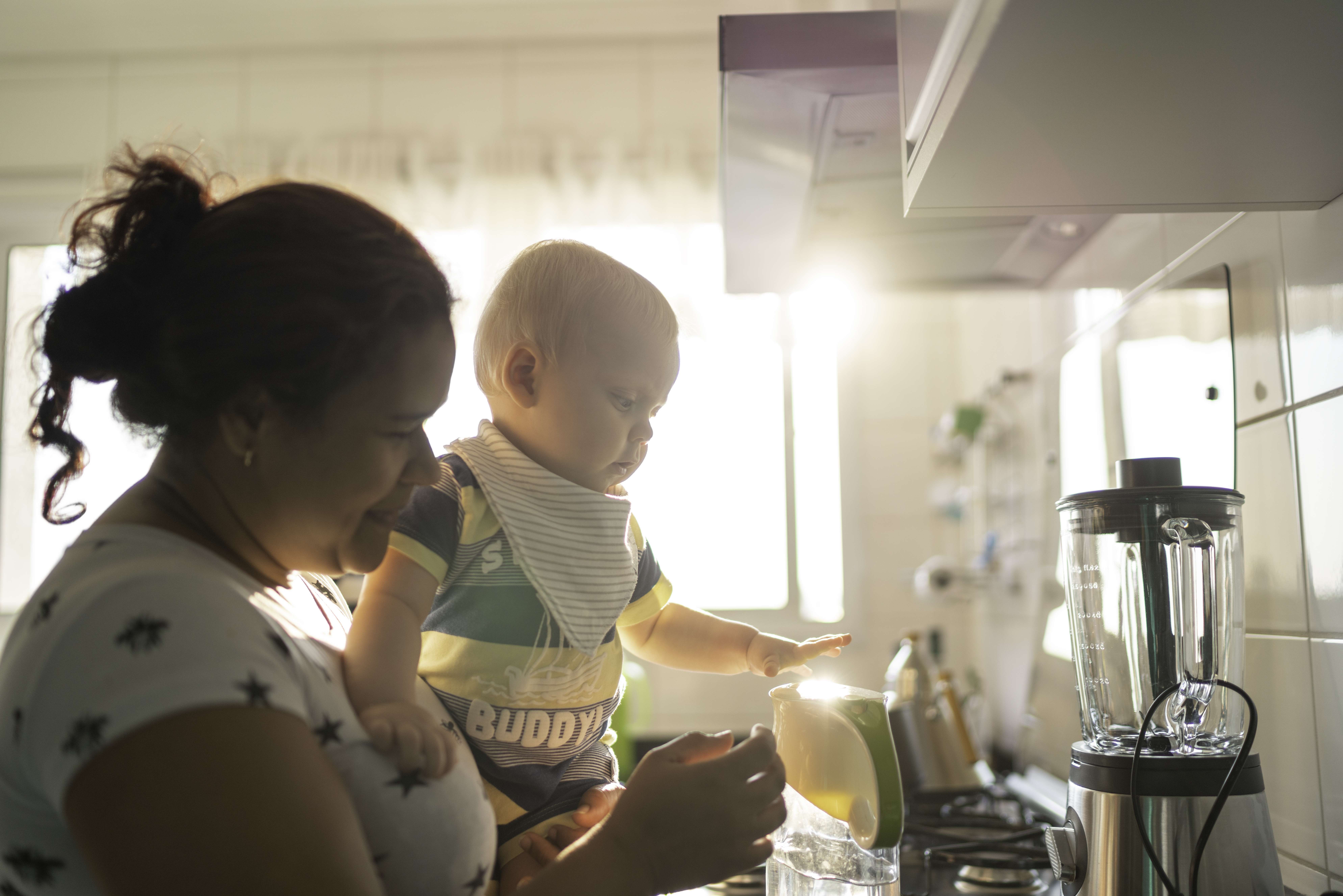 Certified child care provider holding a baby in the kitchen.
