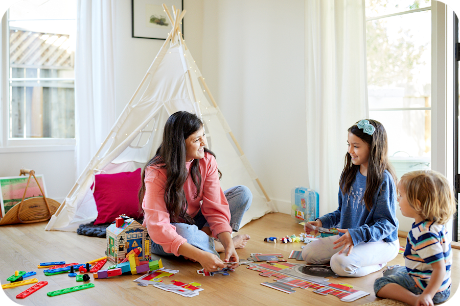 A caregiver playing with children in a bright home