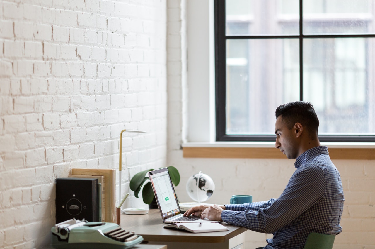 man-sitting-on-green-chair-while-using-laptop-374831