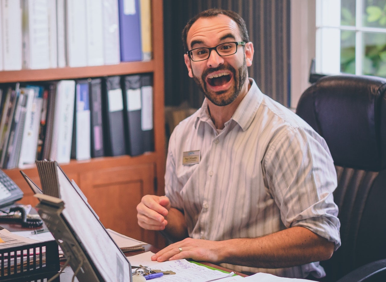 man-laughing-while-sitting-on-office-chair-1546912