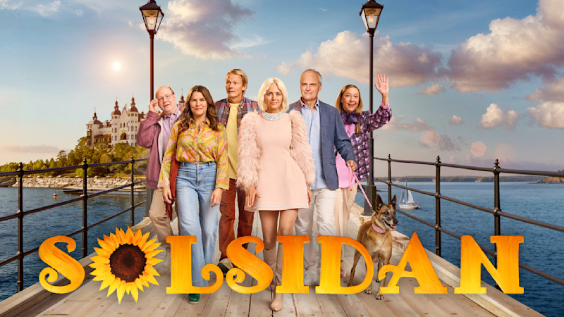En grupp personer står på en brygga vid havet med ett slott i bakgrunden. Texten "SOLSIDAN" visas med en solros.