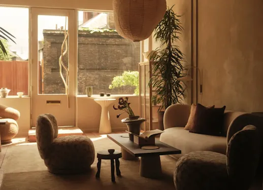 Curved lounge furniture, decorative plants and warm natural light in a living room finished with KABRIC Chestnut.
