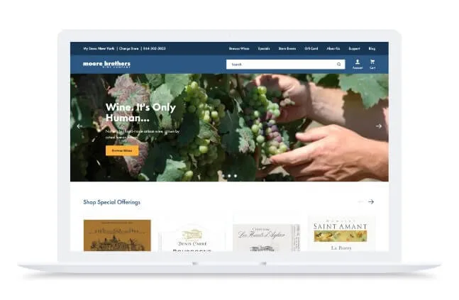 A laptop with Moore Brothers Wine Company’s landing page shows an image of a pair of hands grabbing grapes off of a vine