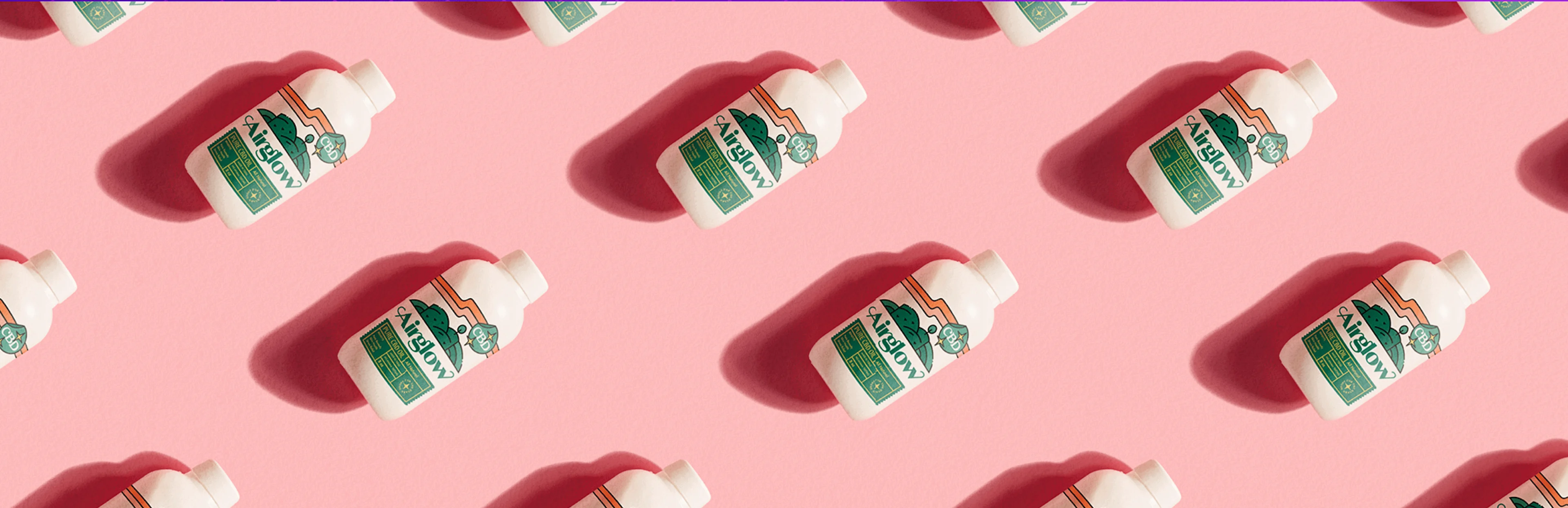 White bottles labeled "CA!glow" with green and orange graphics arranged diagonally on a pink background.