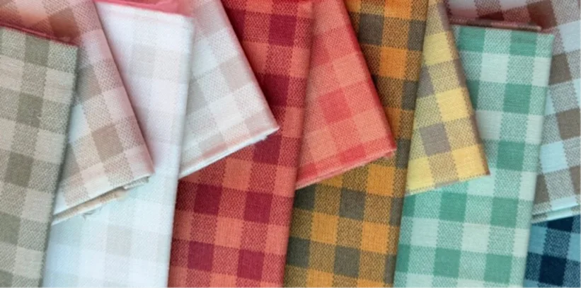 Close-up of folded gingham fabrics in pastel and bright colors, including red, yellow, green, and blue checks