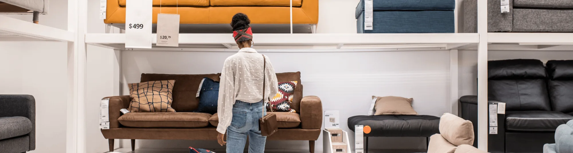 A woman with a red headband looks at sofas in a furniture store, surrounded by couches in various colors and styles.