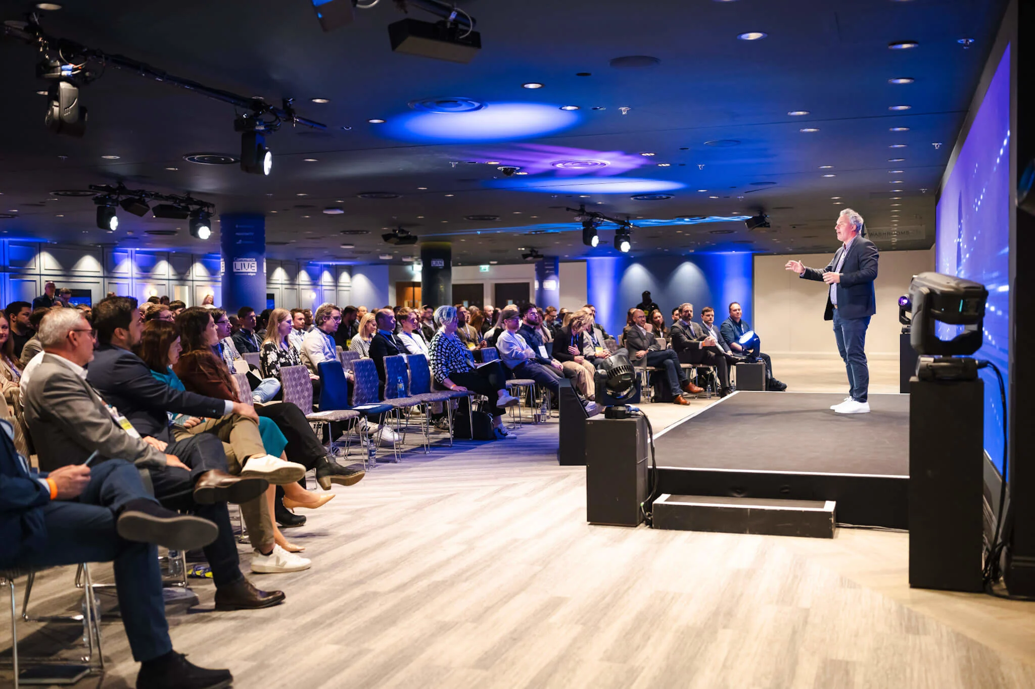 A group of people watching a presentation at the Commerce Live event.