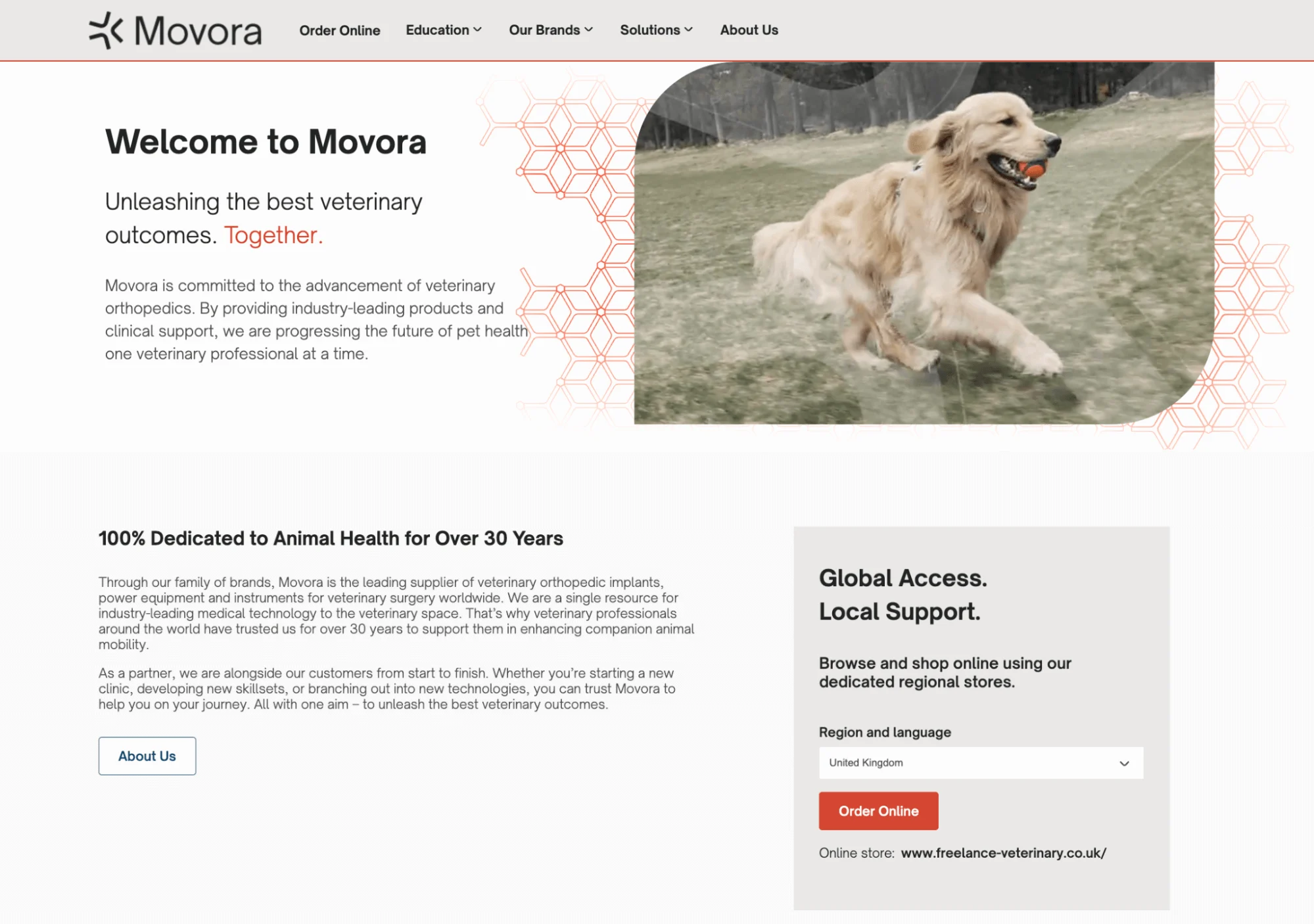 Golden retriever running on grass with an orange ball in its mouth, background of trees and overcast sky.