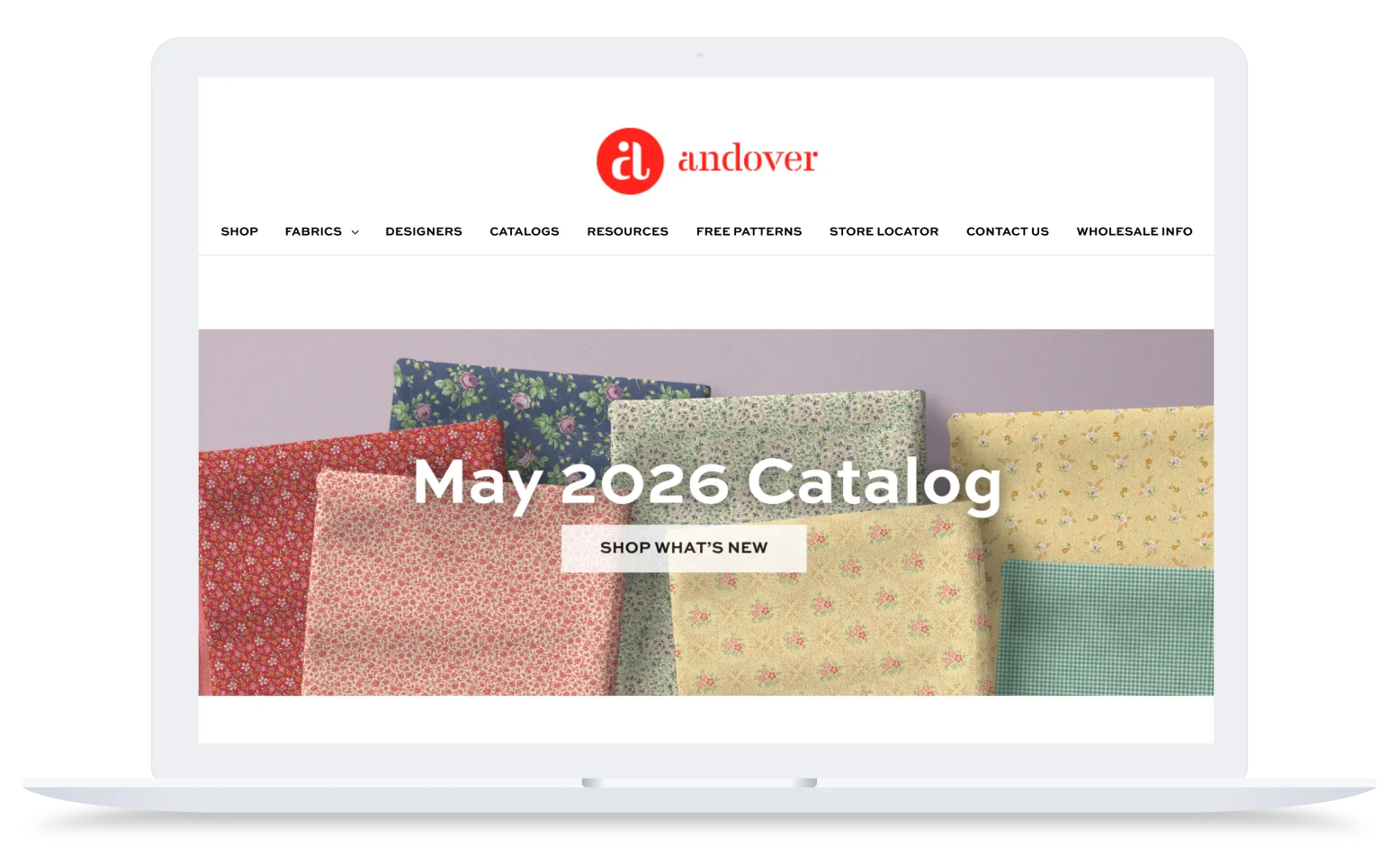 Laptop screen showing Andover website with floral fabric swatches and text “May 2026 Catalog” and “Shop What’s New” button.
