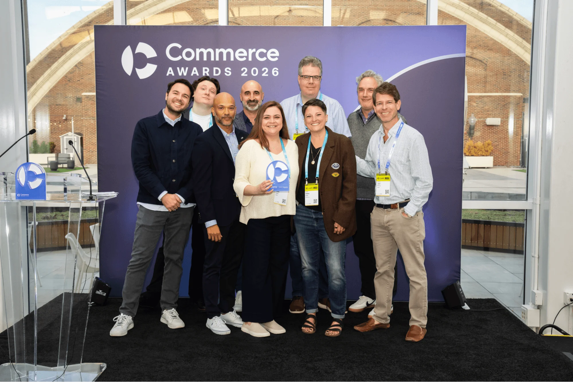 PayPal wins Tech Partner of the Year at the Commerce Awards 2026. Group of award winners posing with trophy in front of a purple Commerce Awards 2026 backdrop, indoors.