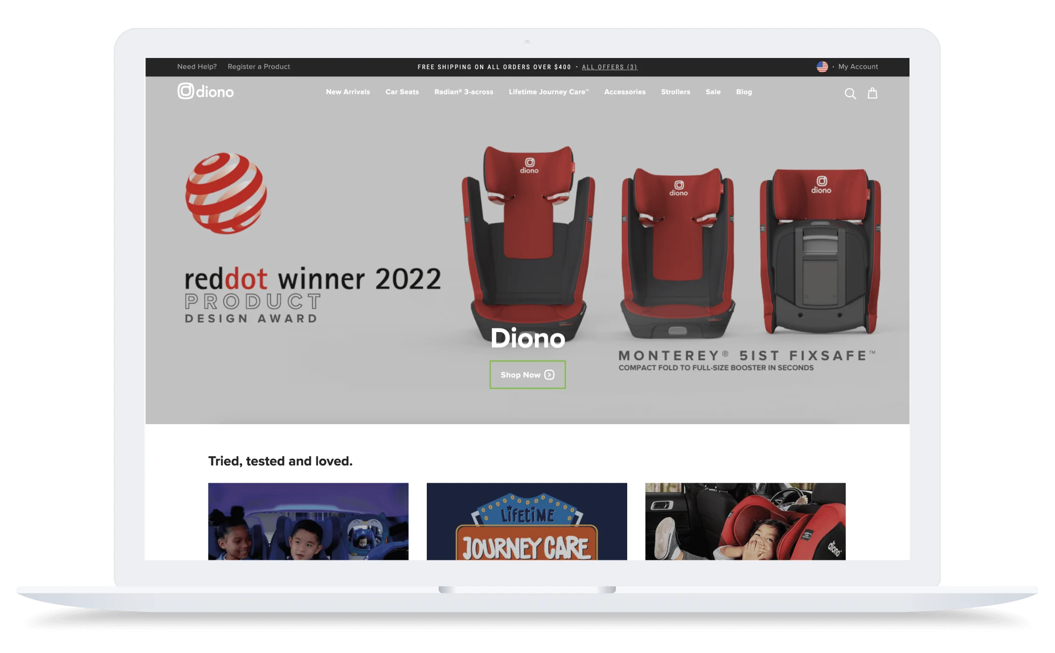 Laptop screen showing Diono website with red car seats, Red Dot Award logo, and navigation menu at the top.