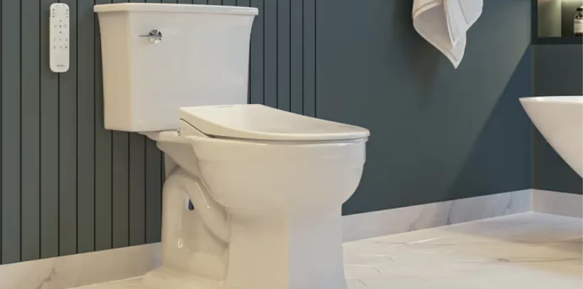 Modern white toilet with a bidet seat in a clean bathroom with dark paneled walls and light tile flooring.