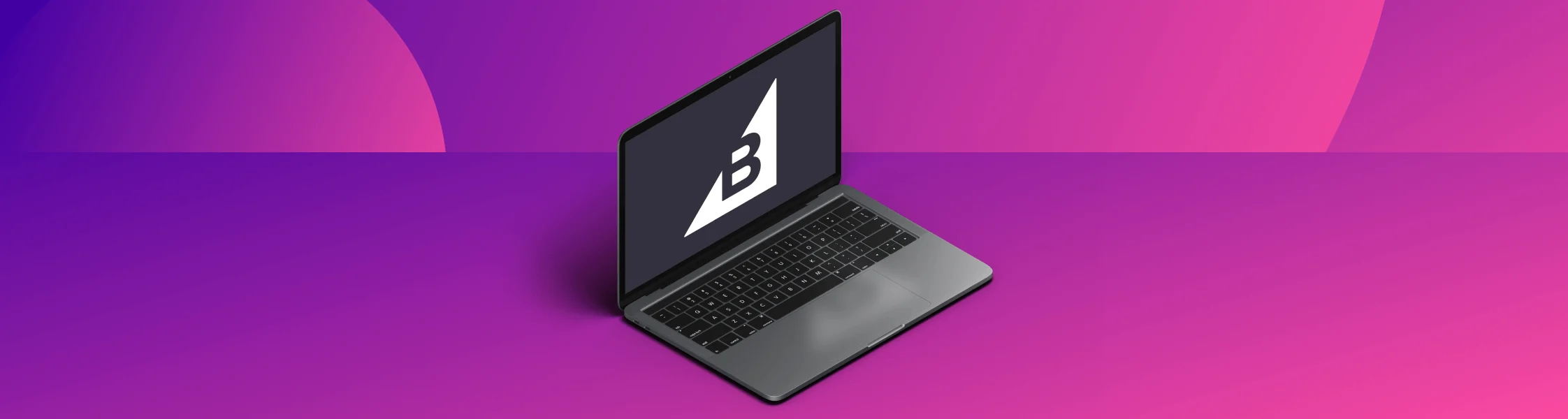 A laptop with a black screen displaying a white BigCommerce logo on a black screen, on a pink and purple gradient background.