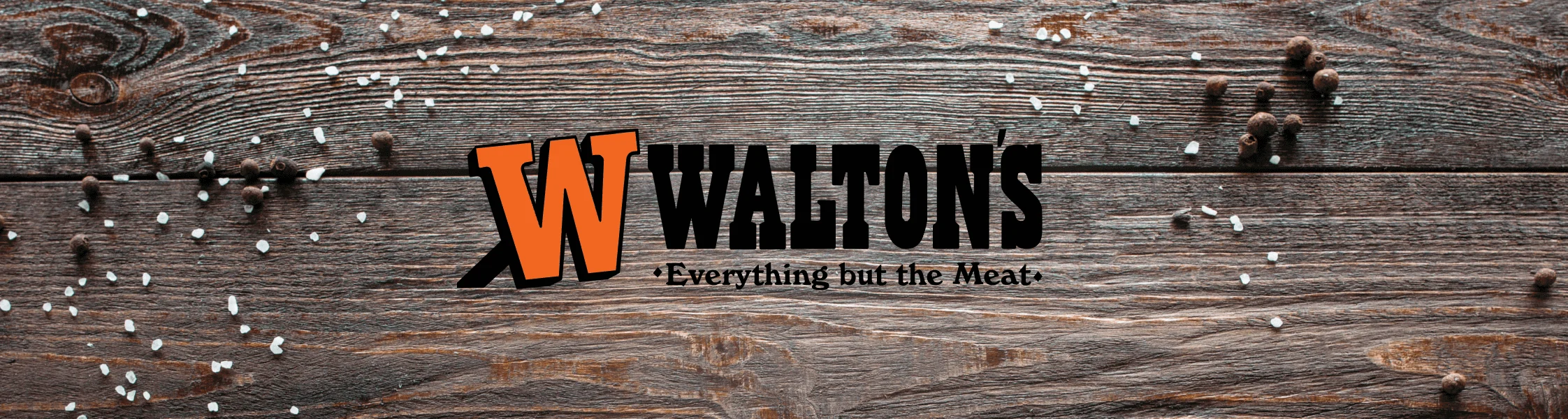 Walton’s logo with slogan “Everything but the Meat” on rustic wood, scattered salt crystals and peppercorns.