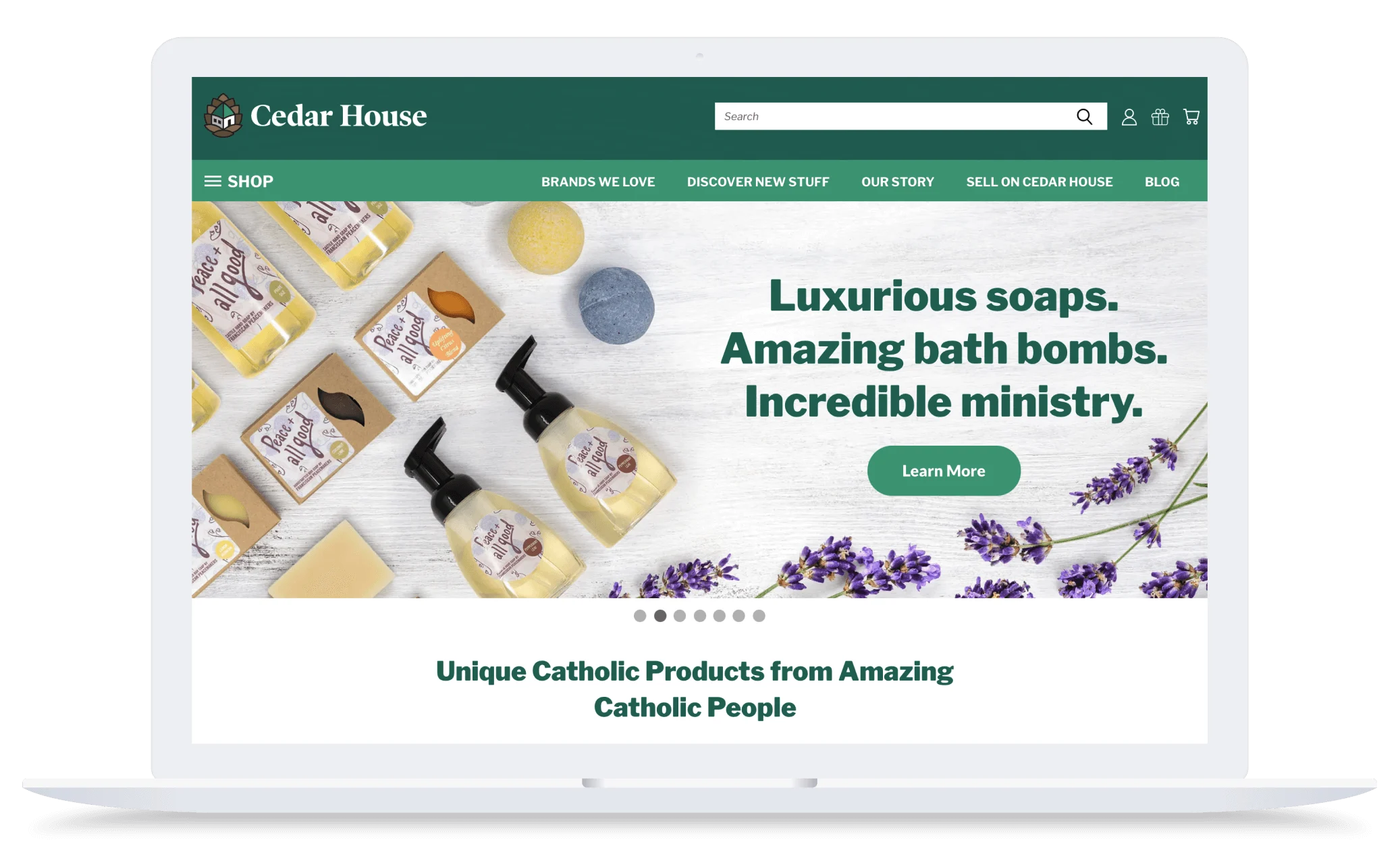 Laptop screen showing Cedar House website with soaps, bath bombs, lavender, and text about luxurious products and ministry.