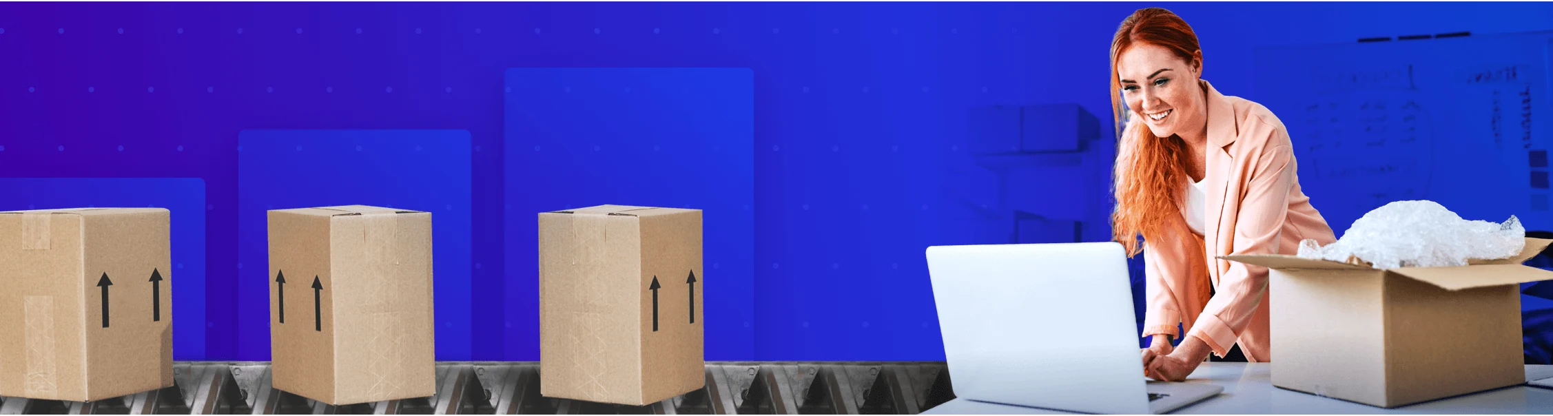 Smiling woman in a peach jacket works on a laptop near open and sealed cardboard boxes on a blue background.