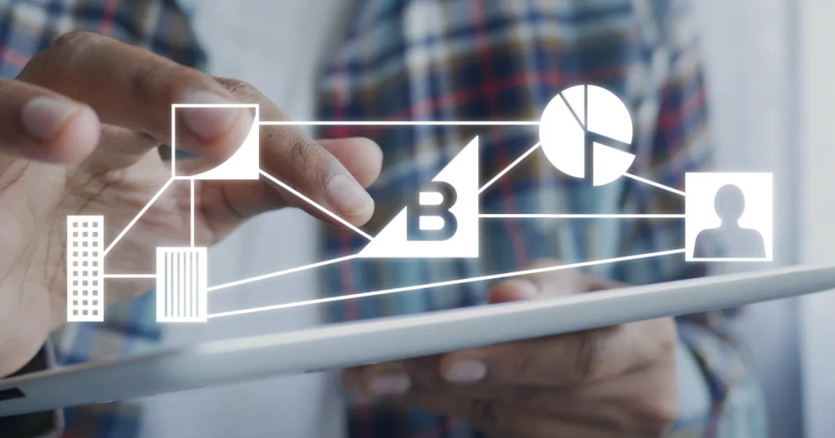 Person using tablet with digital business icons, charts, and network connections overlayed on the screen.