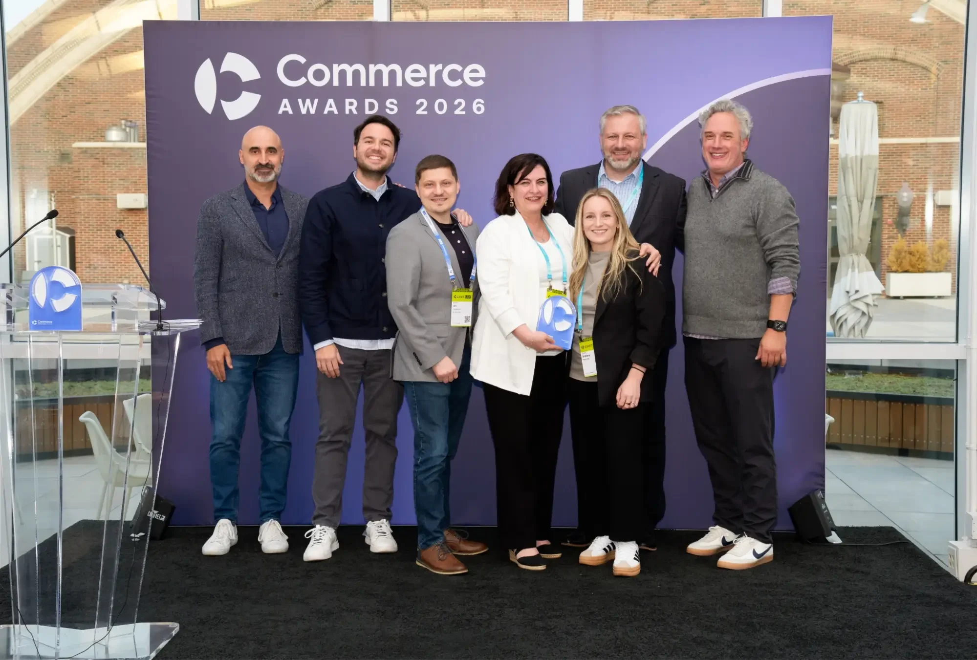 Mojo Active wins Agency Partner of the Year at the Commerce Awards 2026. Group of seven posing with a trophy in front of a purple “Commerce Awards 2026” backdrop at an event venue.
