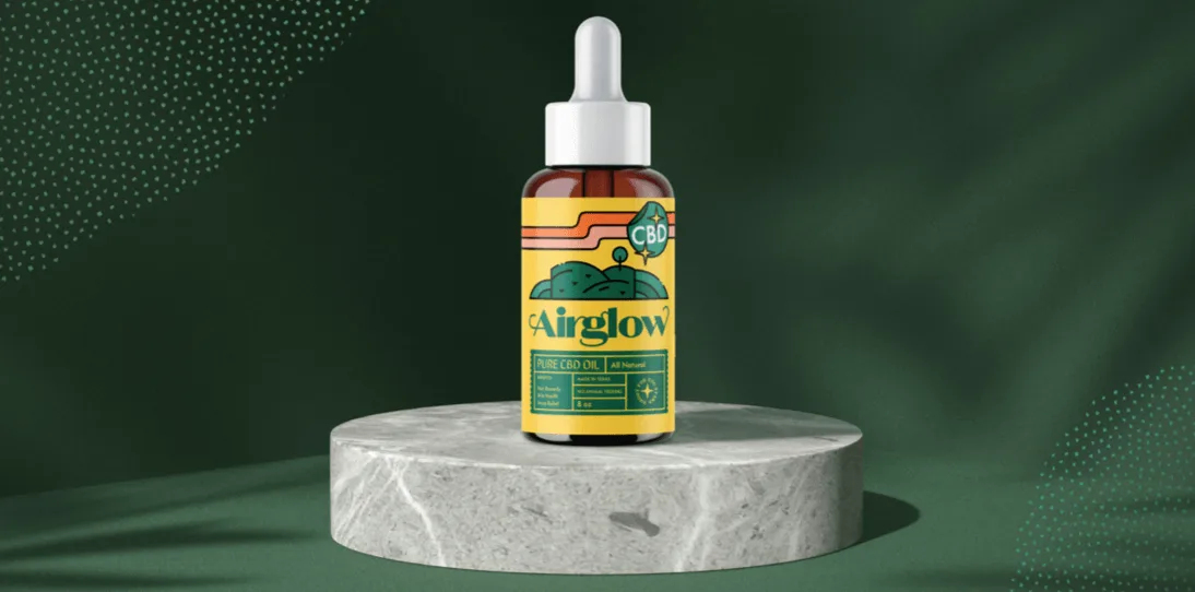 A bottle of Airglow Pure CBD Oil with a yellow label sits on a round marble pedestal against a green background.