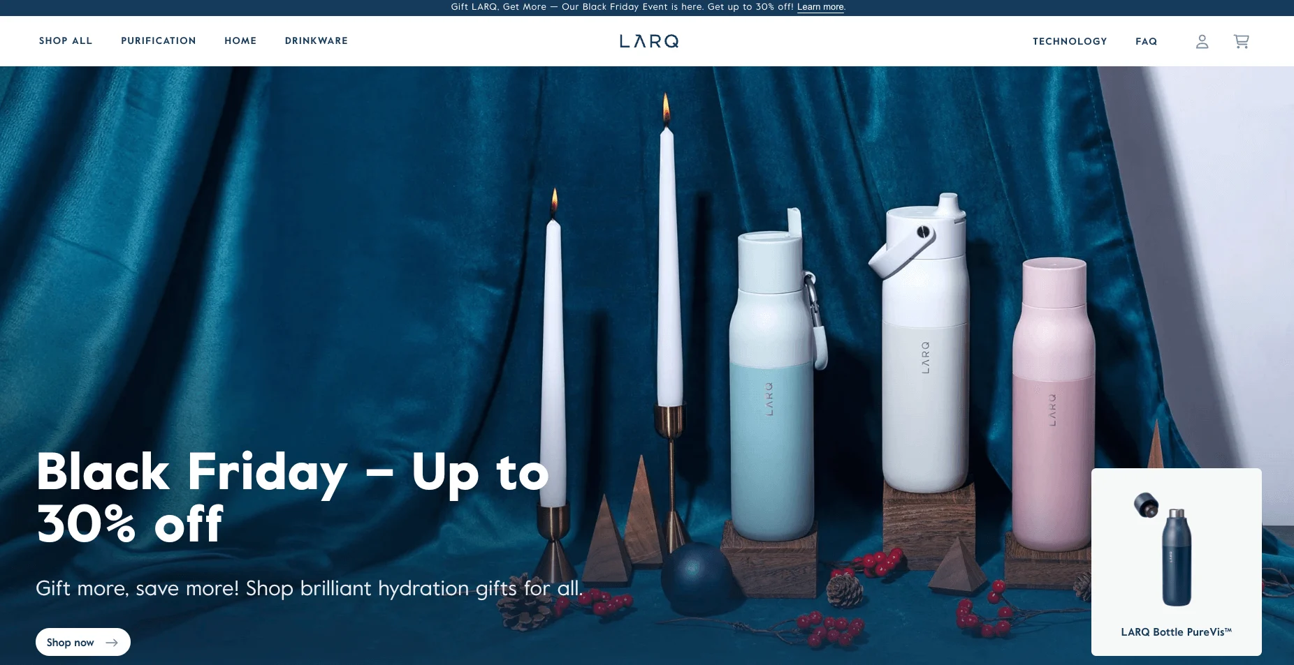 Three LARQ water bottles in pastel colors, two lit candles, and holiday decor on a blue velvet background.