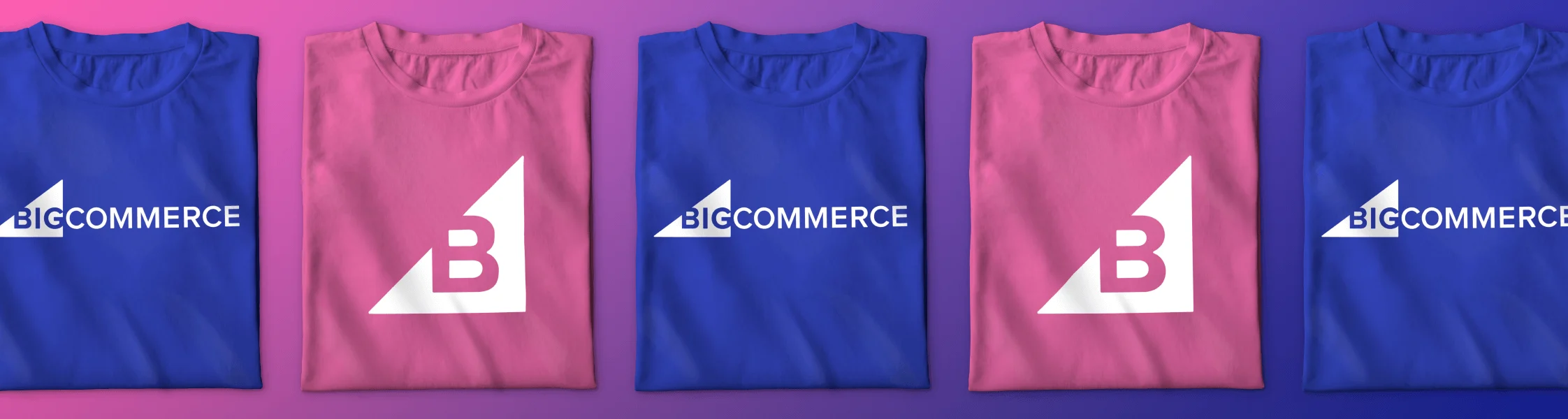 Five folded t-shirts in alternating blue and pink, each with a white BigCommerce logo or stylized "B" design.