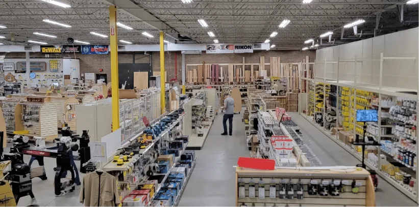 Interior of a large hardware store with aisles of products, yellow support columns, and industrial ceiling lighting.
