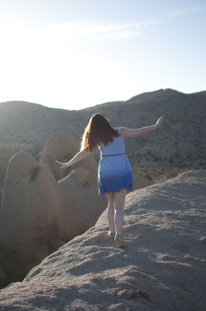 Girl walking on a mountain with arms out. 