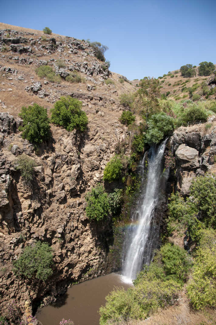 Waterfall with rainbow from afar in Jilabun Stream, Golan Heights, Israel. 