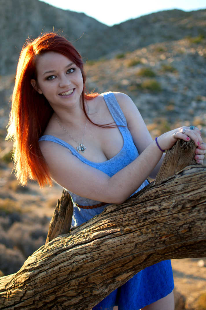 Girl leaning over a tree trunk.