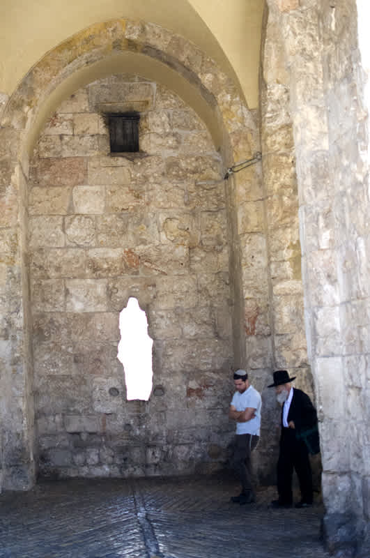 Two men talking near a roughly cut window in Jerusalem, Israel