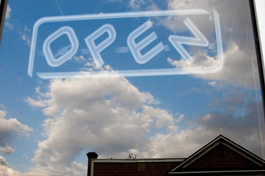 Blue sky reflected in window with Open sign in Banning, California. 