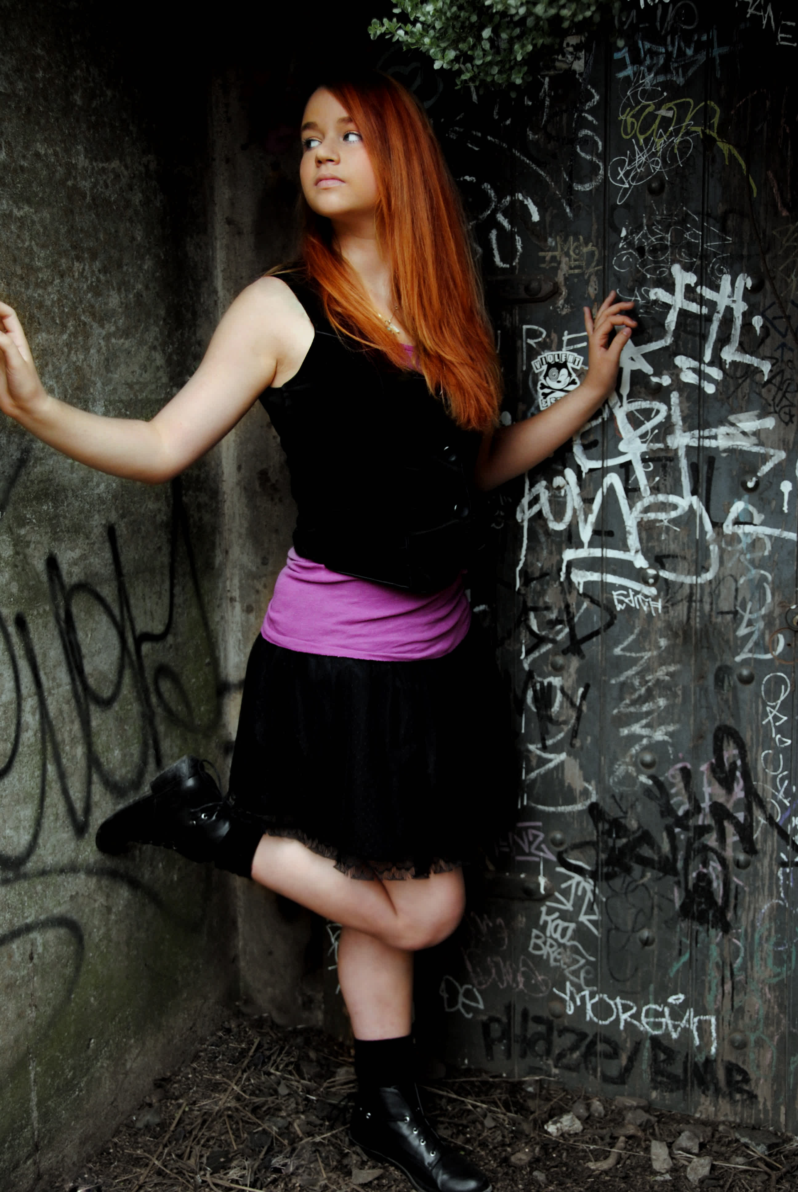 Girl posing in front of a wall covered in graffiti. 