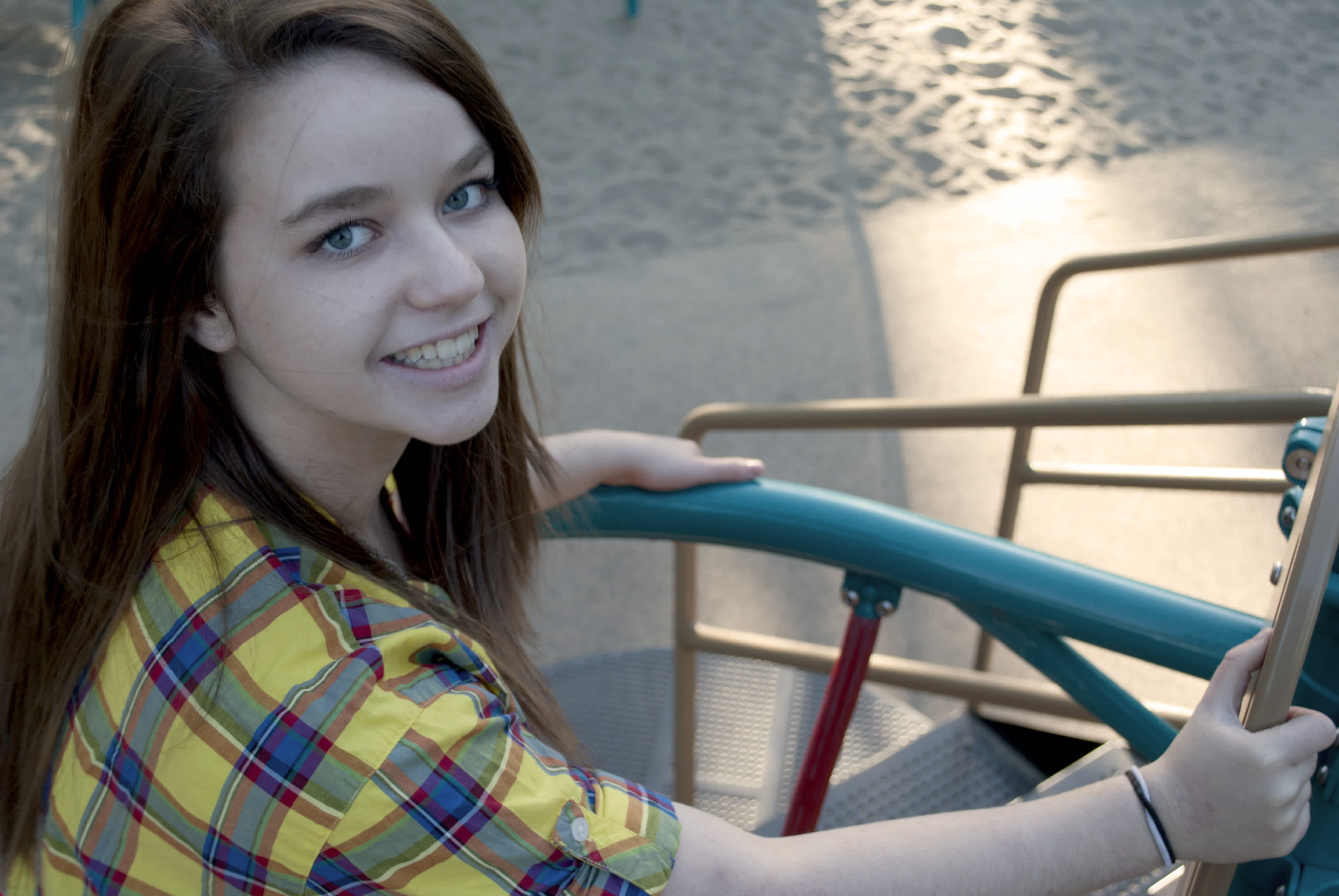Girl wearing yellow and blue plaid in front of railing.