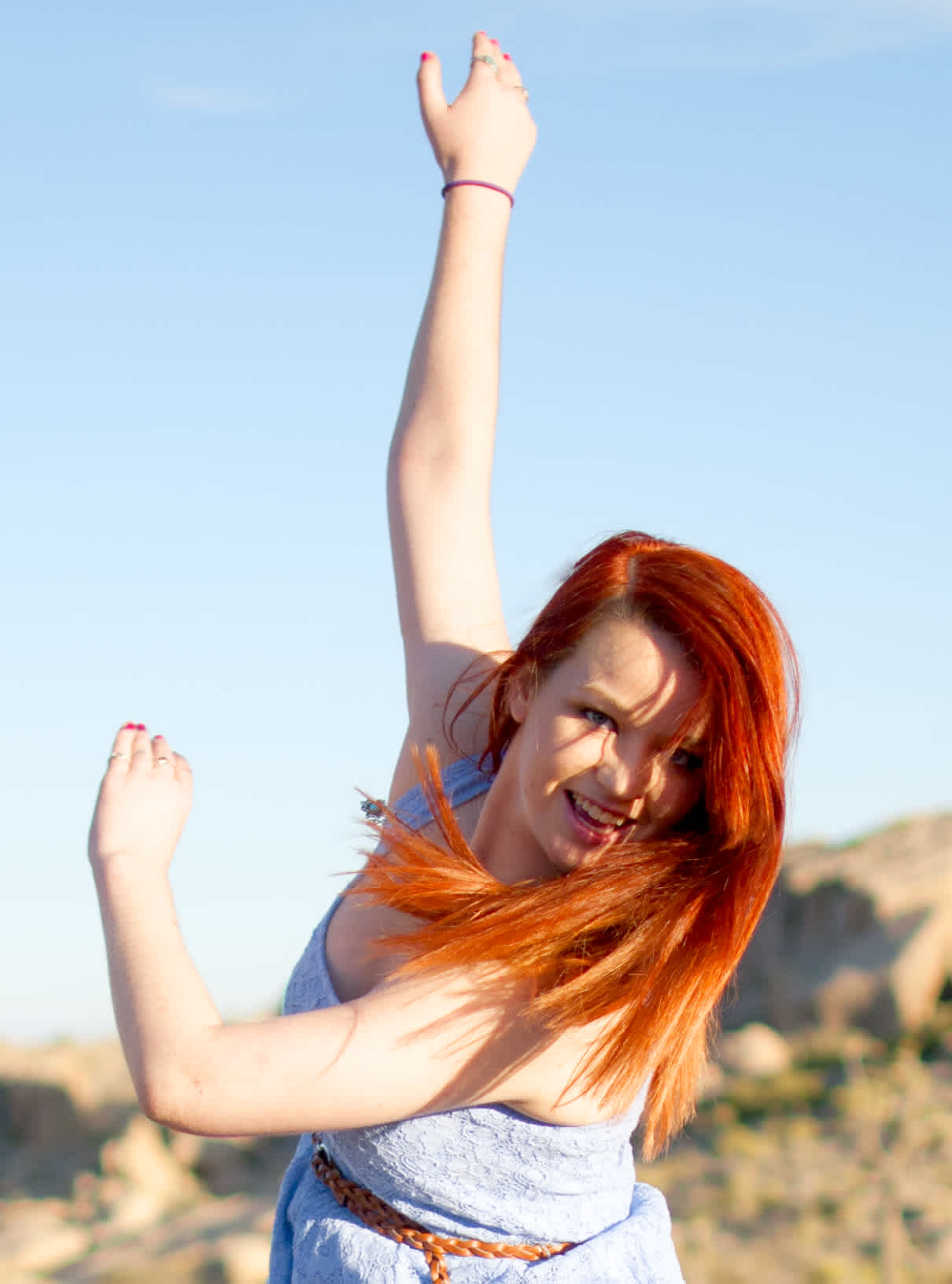 Girl dancing with arms waving in sunlight. 
