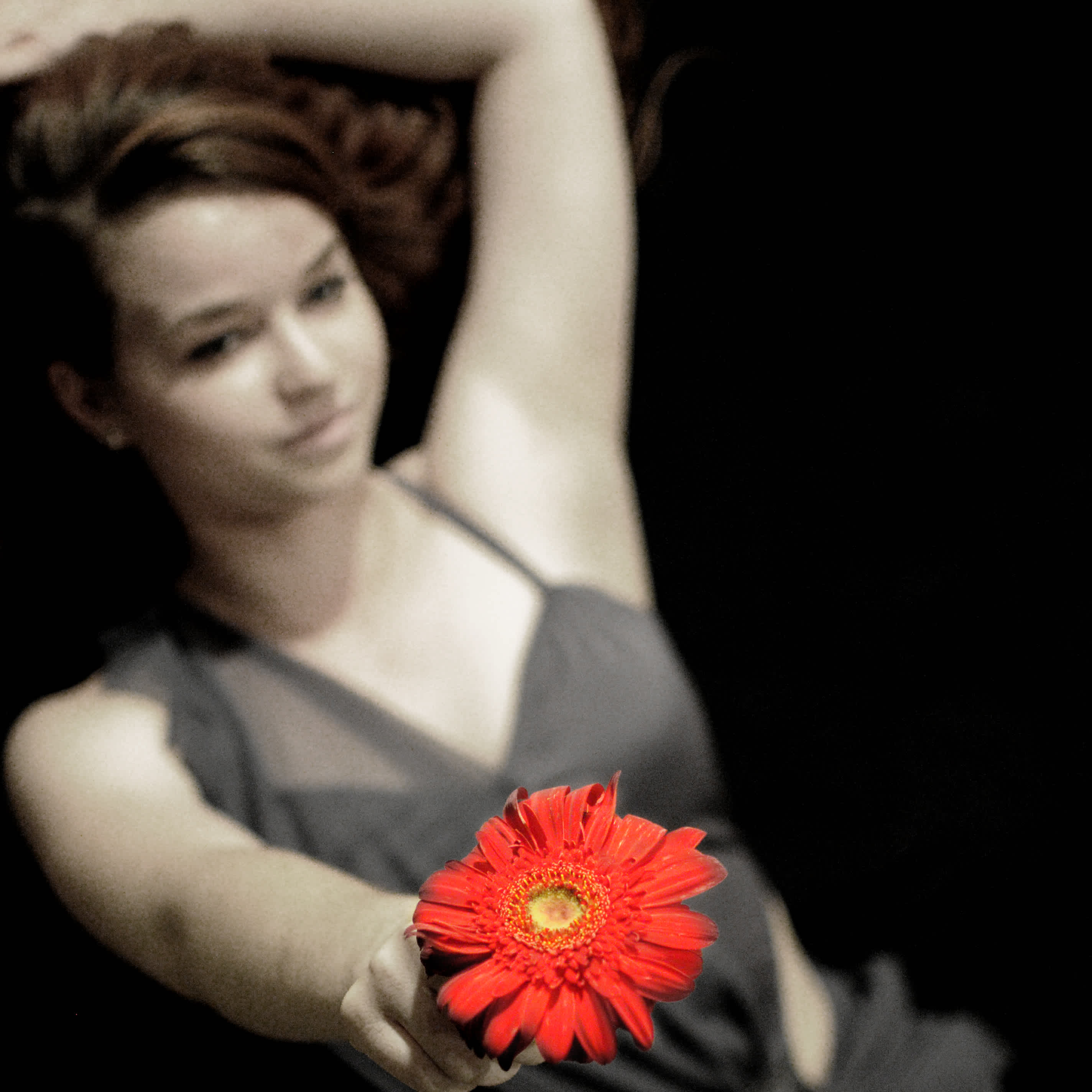 Girl laying down holding up a flower.