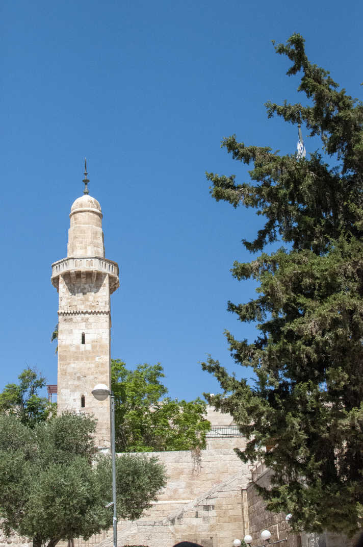 Tower on a building partially obscured by trees in Jerusalem, Israel