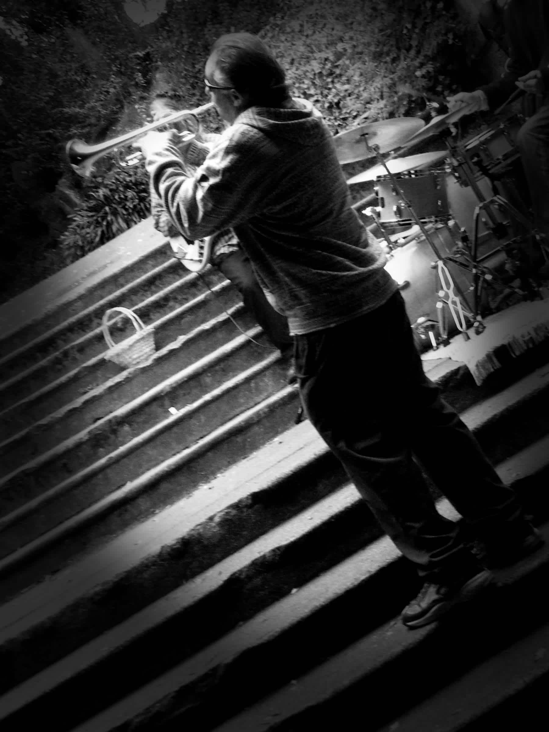 Man playing trumpet on a stairwell in black and white in Golden Gate Park, San Francisco, California.